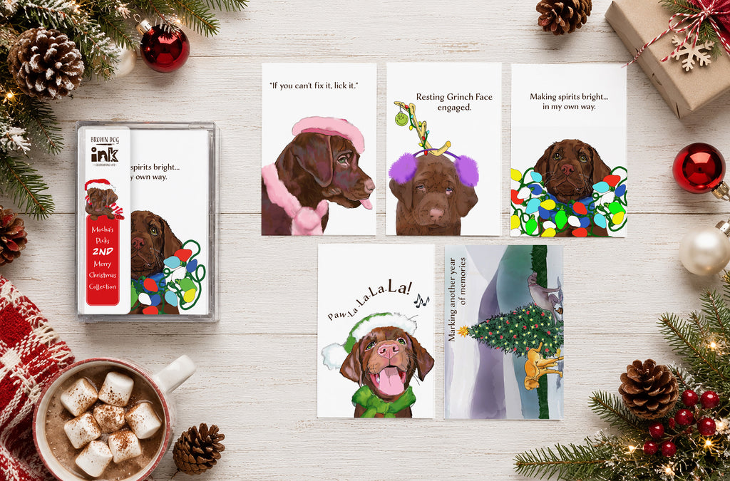 Mocha’s 2nd Merry Christmas Collection featuring five dog Christmas cards with original artwork by Susan J. York, displayed with clear packaging on a festive holiday flat lay with ornaments, pine branches, and hot cocoa.