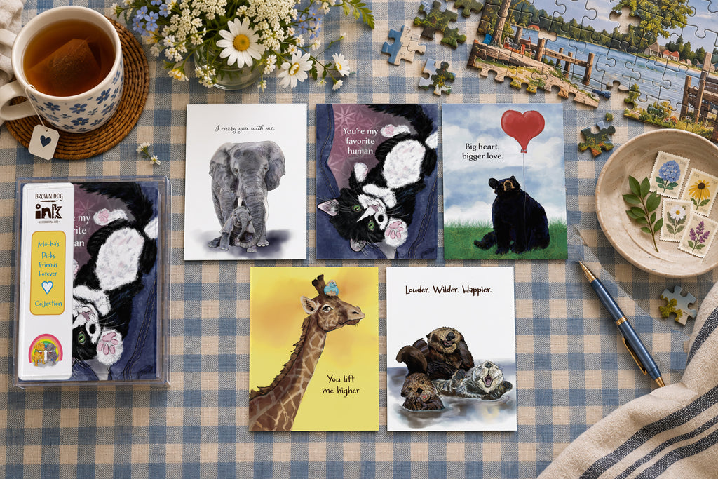 Friends Forever greeting card collection featuring five illustrated friendship cards with original artwork by Susan J. York, including an elephant, cat, bear, giraffe and otters, displayed with Brown Dog Ink packaging on a cozy gingham tabletop.