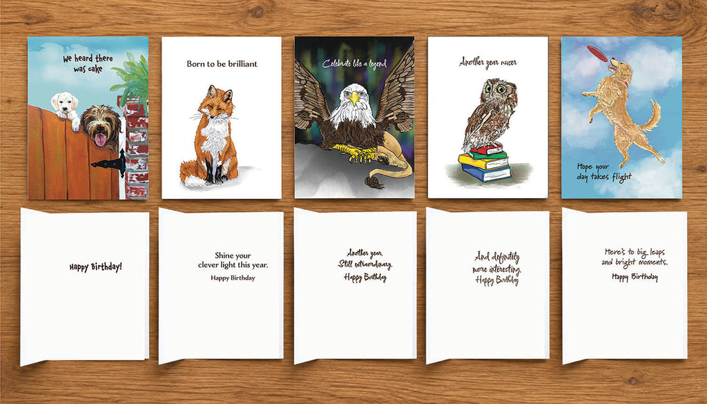 Five illustrated animal birthday cards by Susan J. York arranged on a wooden surface, showing the colorful front artwork and coordinating inside birthday messages.