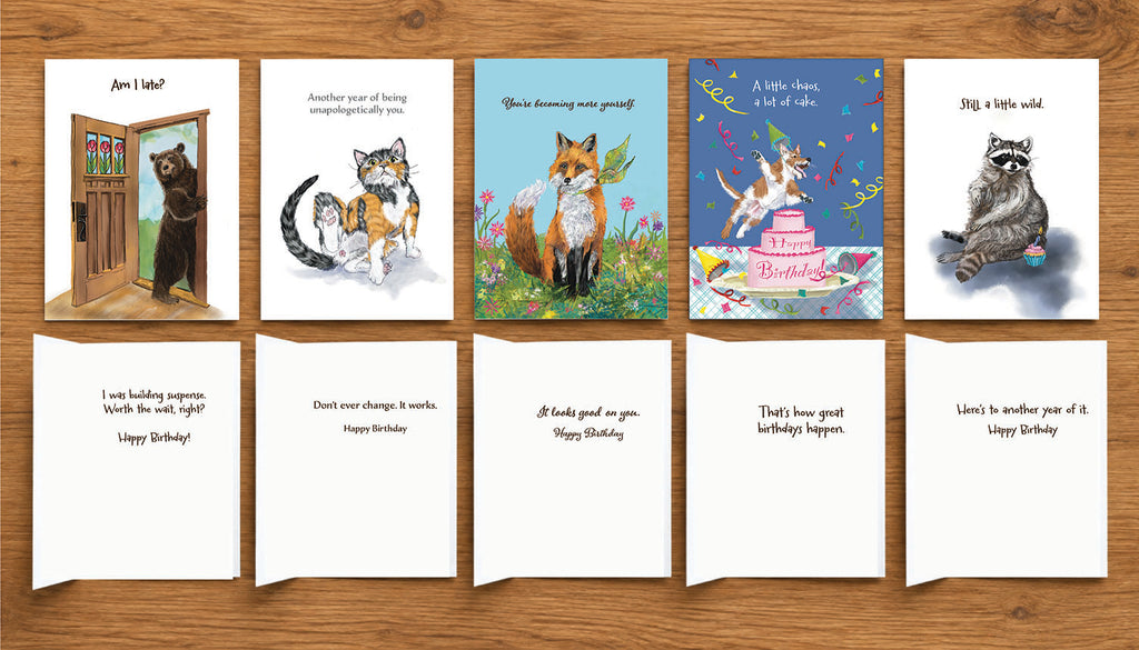Five illustrated animal birthday cards by Susan J. York arranged on a wooden surface, showing colorful front artwork and coordinating inside birthday messages.